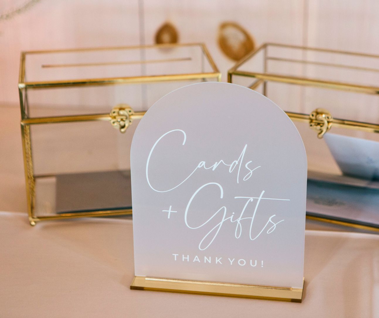 Wedding card and gift sign displayed on a table with glass card boxes behind it.