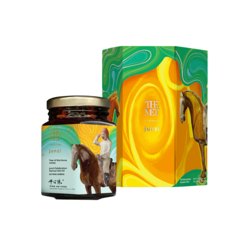 A jar of chili oil next to a decorative box with a swirling green, orange and yellow design.