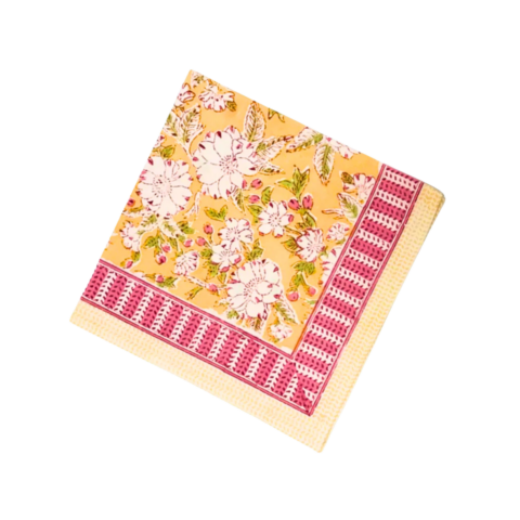 A yellow square napkin with a floral pattern and pink striped border.