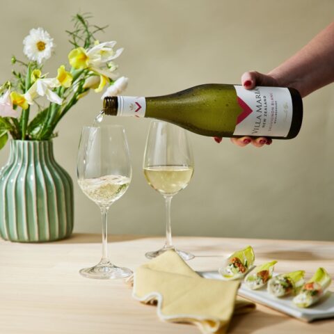 Villa Maria Marlborough Sauvignon Blanc being poured into wine glasses alongside light appetizers.
