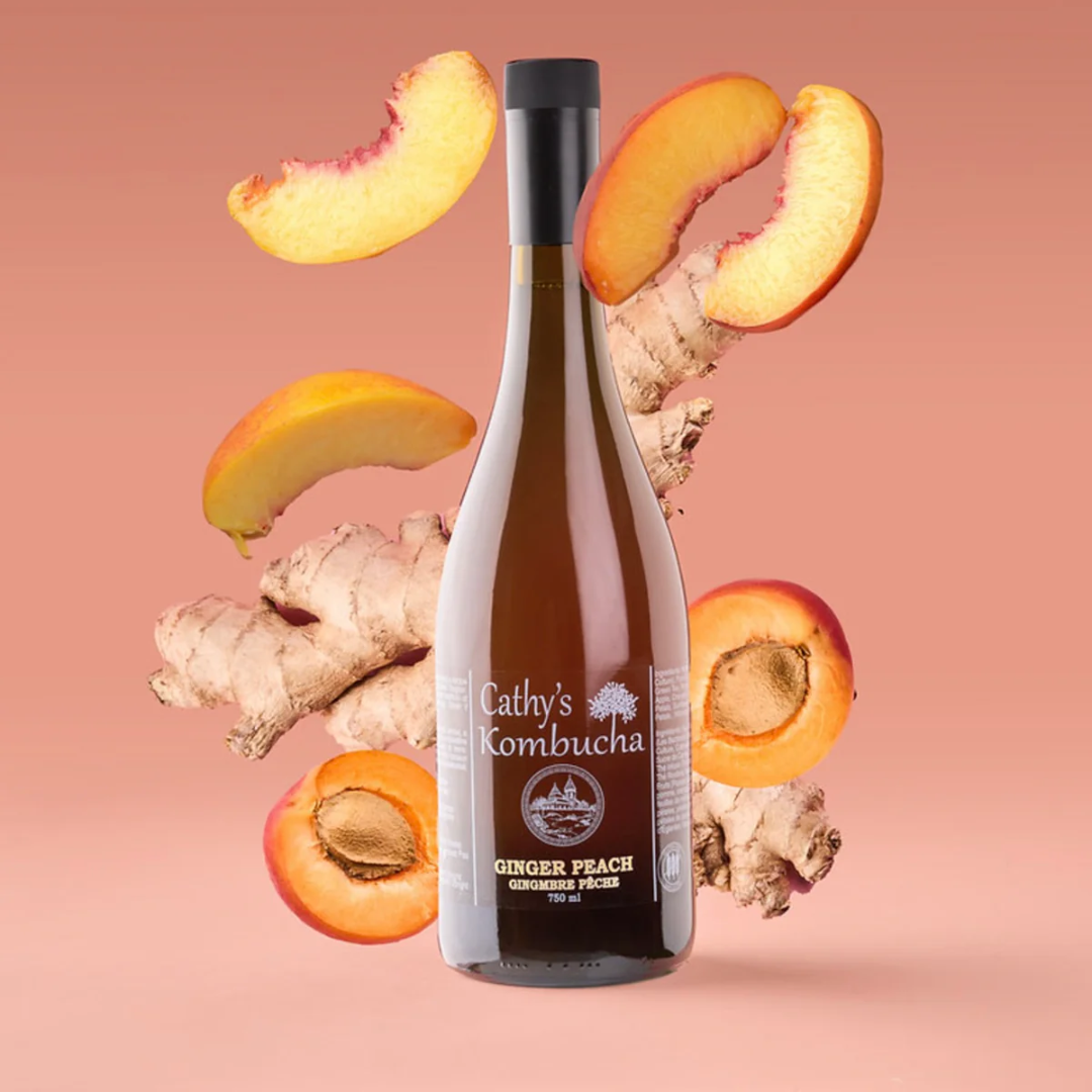 A brown bottle of kombucha in front of floating pieces of ginger and peaches.