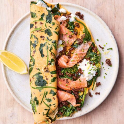 Herb-flecked omelet folded over smoked salmon, sautéed greens and dollops of cottage cheese, finished with crispy bits and a lemon wedge on the side.