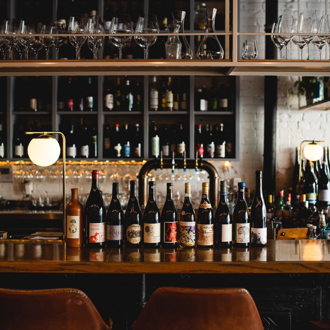 A bar with eleven bottles on wine on the counter.
