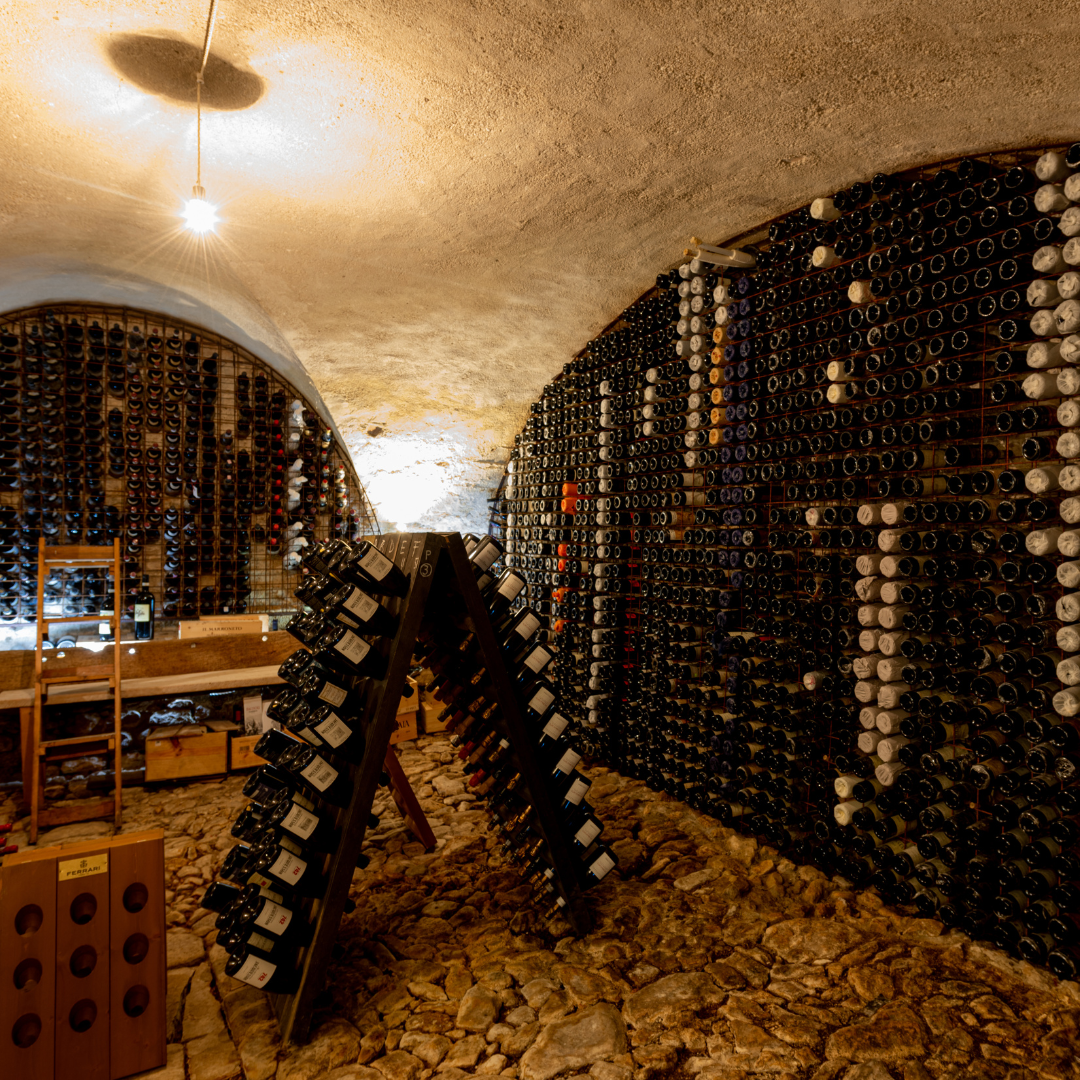 A wine cellar with a warm overhead light and walls lined with bottles. 