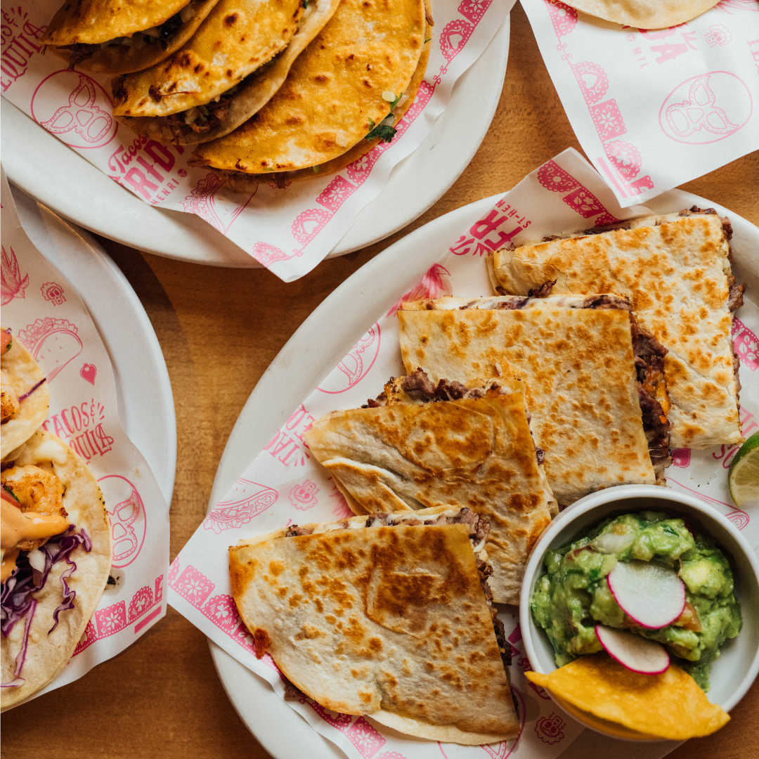 Plates of tacos and quesadillas with a side of guacamole.