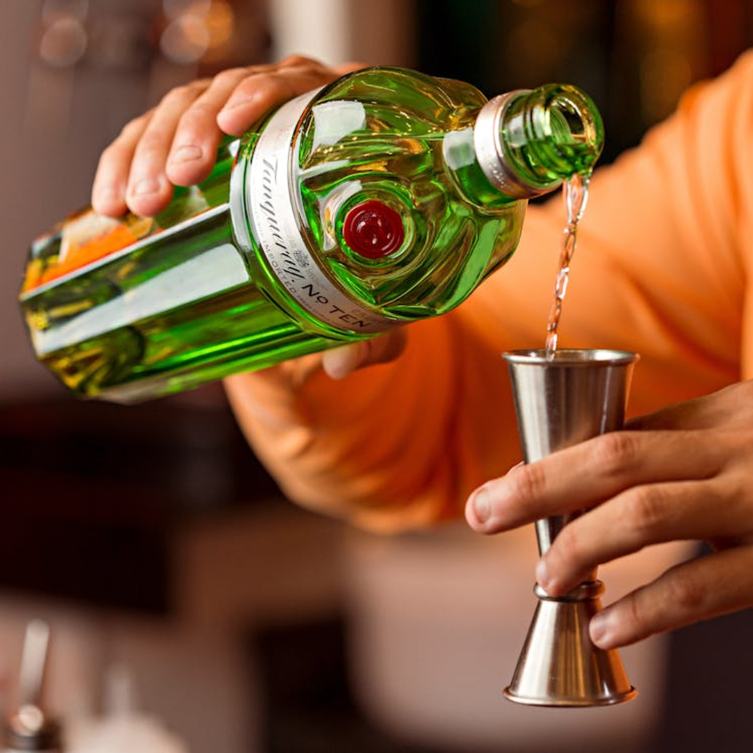 Close-up of a hand pouring Tanquery No. Ten gin from the bottle into a jigger. 