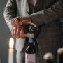 Close-up of two hands using a wine opener to uncork a bottle.