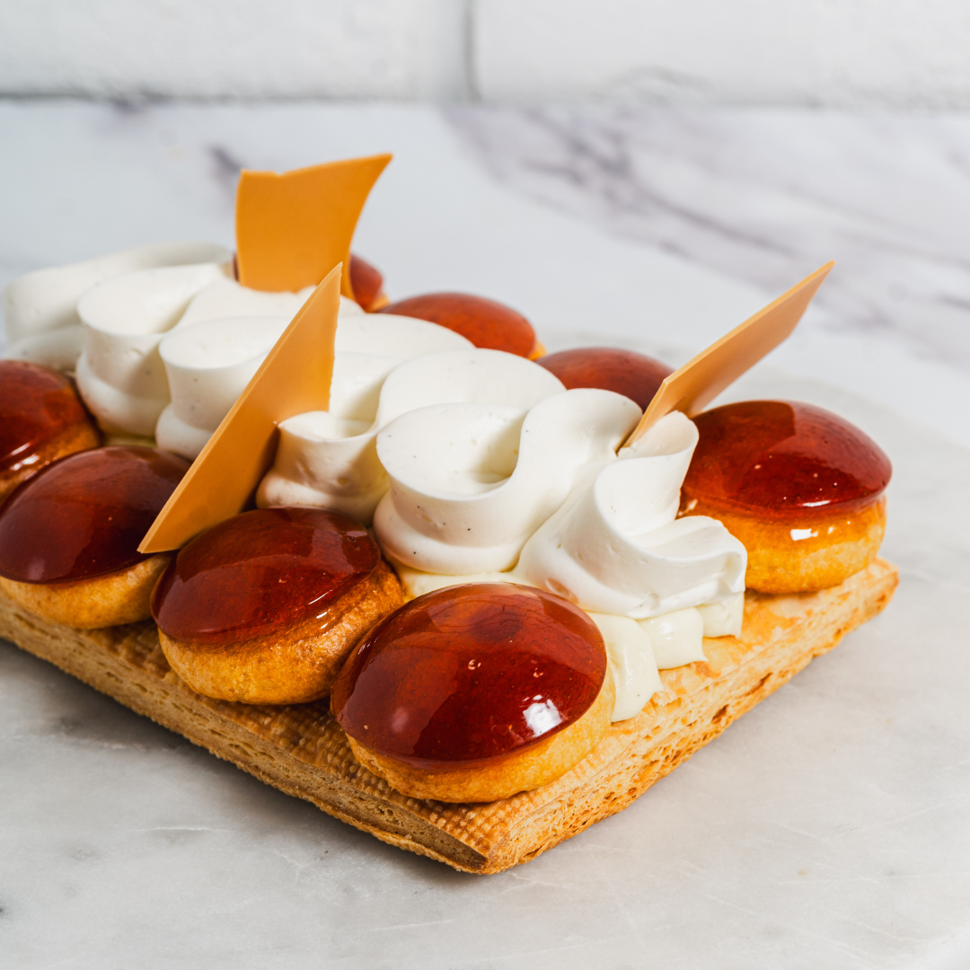 A rectangular Saint-Honoré cake on a white marble countertop.