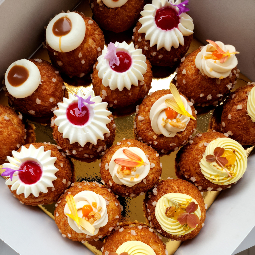 Overhead shot of a box of colourful chouquettes. 