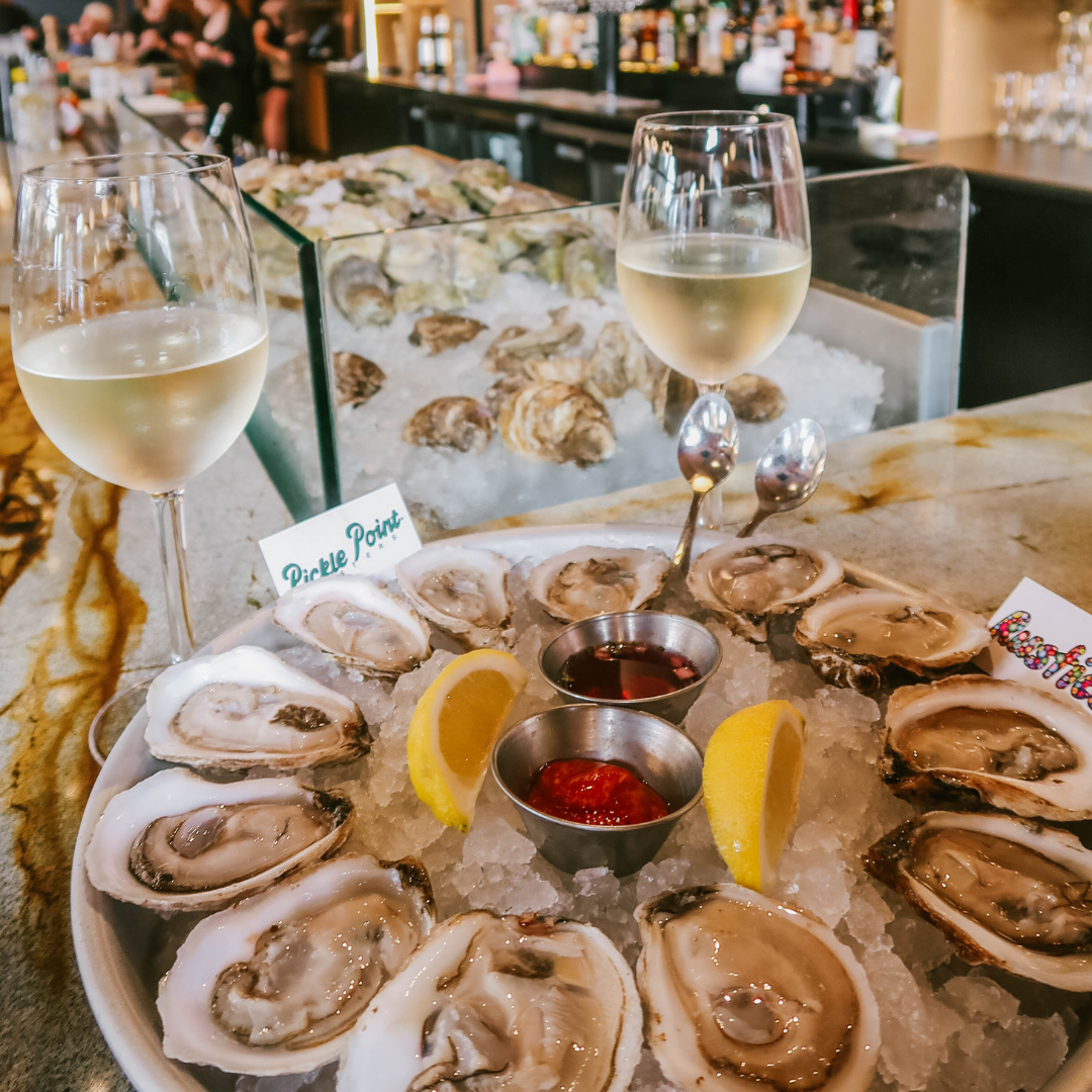 A plate of oysters and two glasses of white wine.