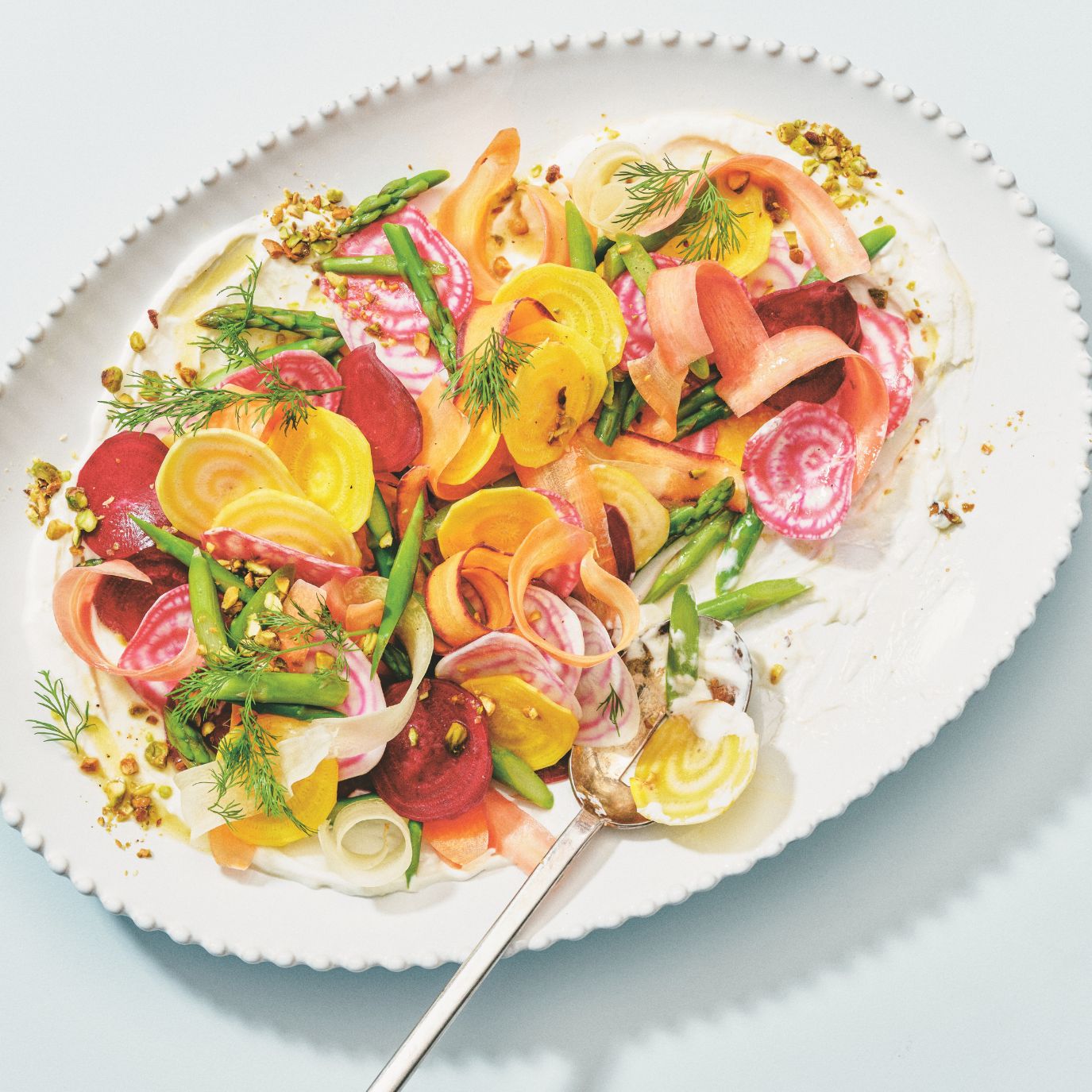 Shaved carrot, asparagus and beet salad dressed with pistachios and creamy dressing in a rainbow and goat cheese salad