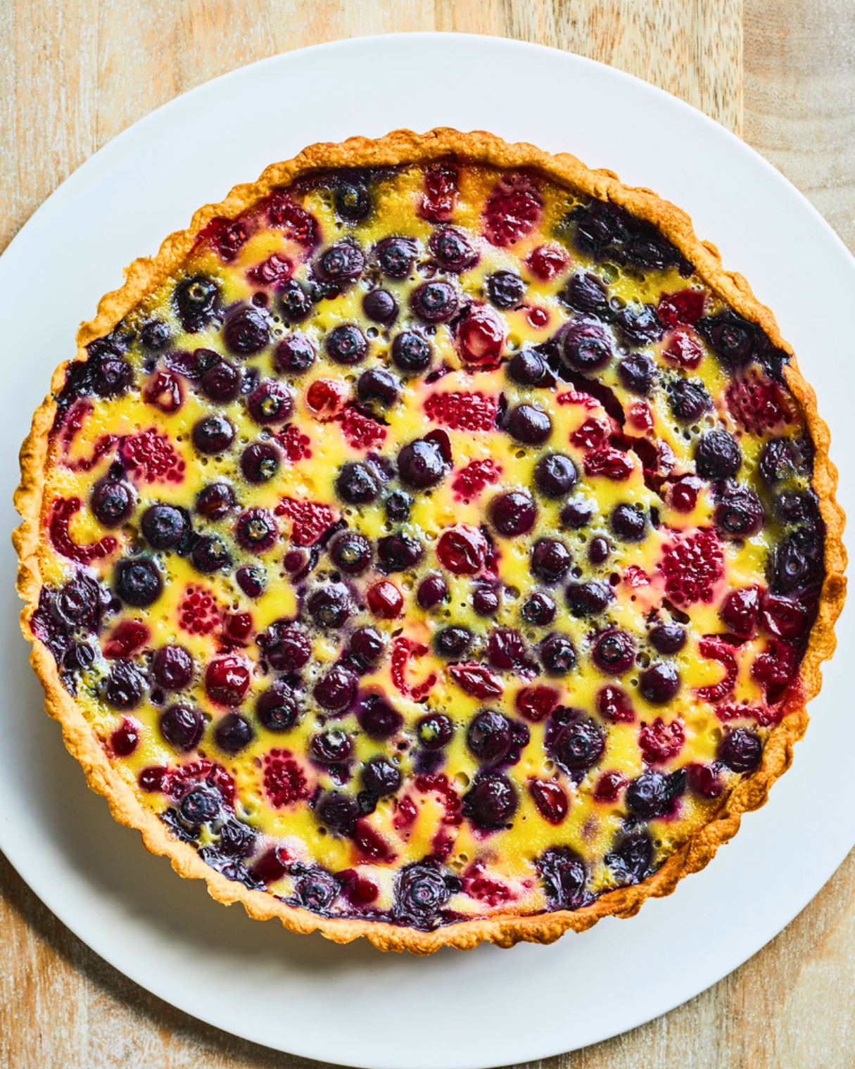 Cherry and berry clafoutis tart with sweet-tart cherries, blueberries and baked vanilla custard in a buttery pastry shell.